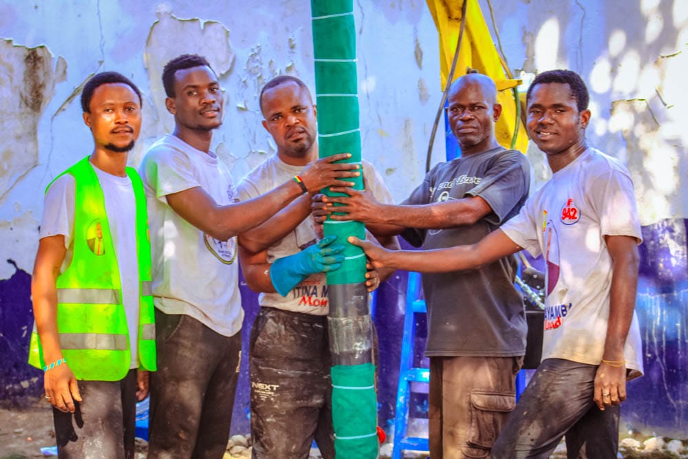 Team installing a water pipe wrapped for a new well connection